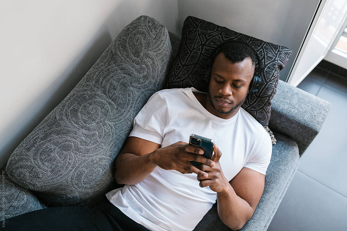 Black meloman using smartphone on couch
