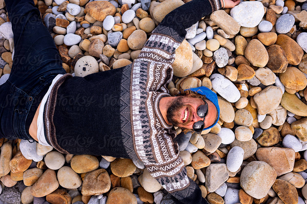 A young man hanging lying on a beautiful beach of yellow rocks