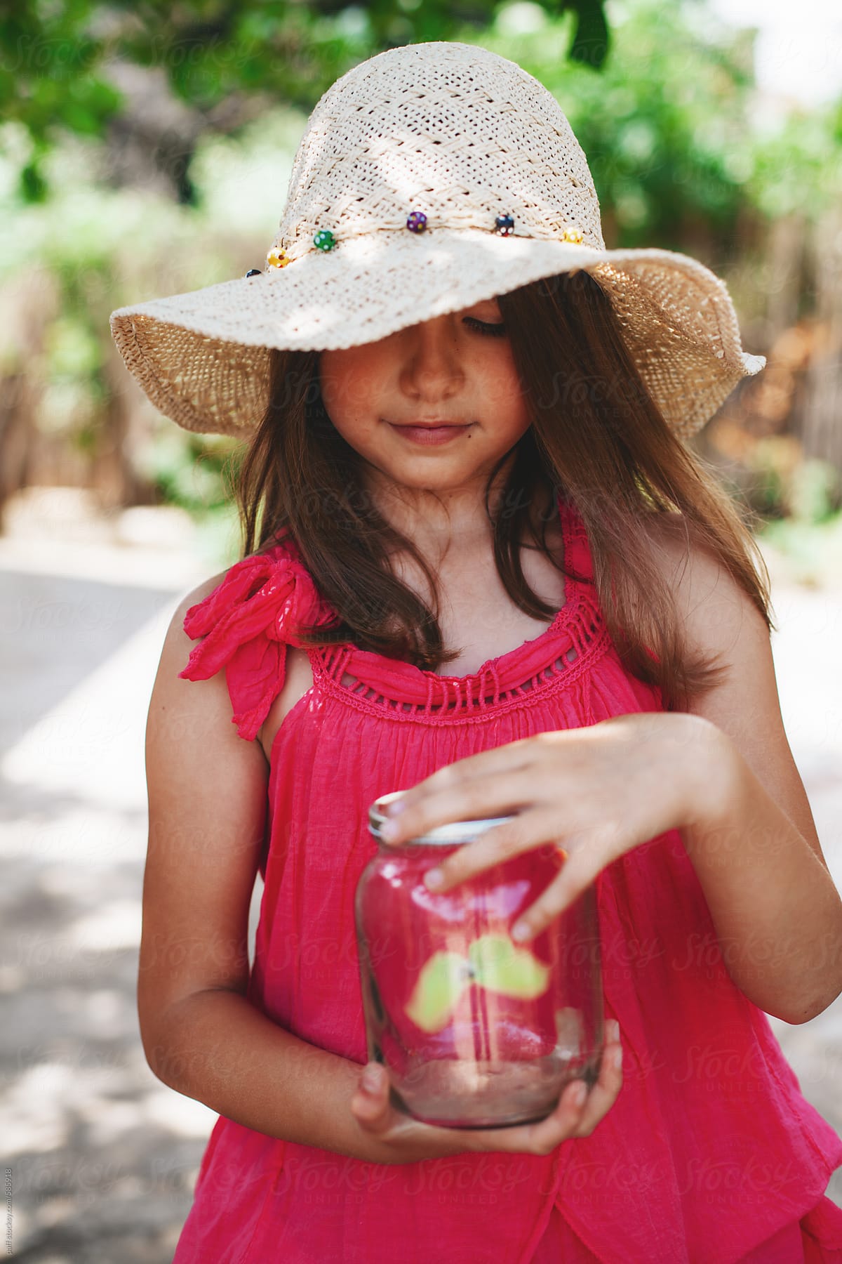 Summer portrait of a little girl holding a jar with butterfly in