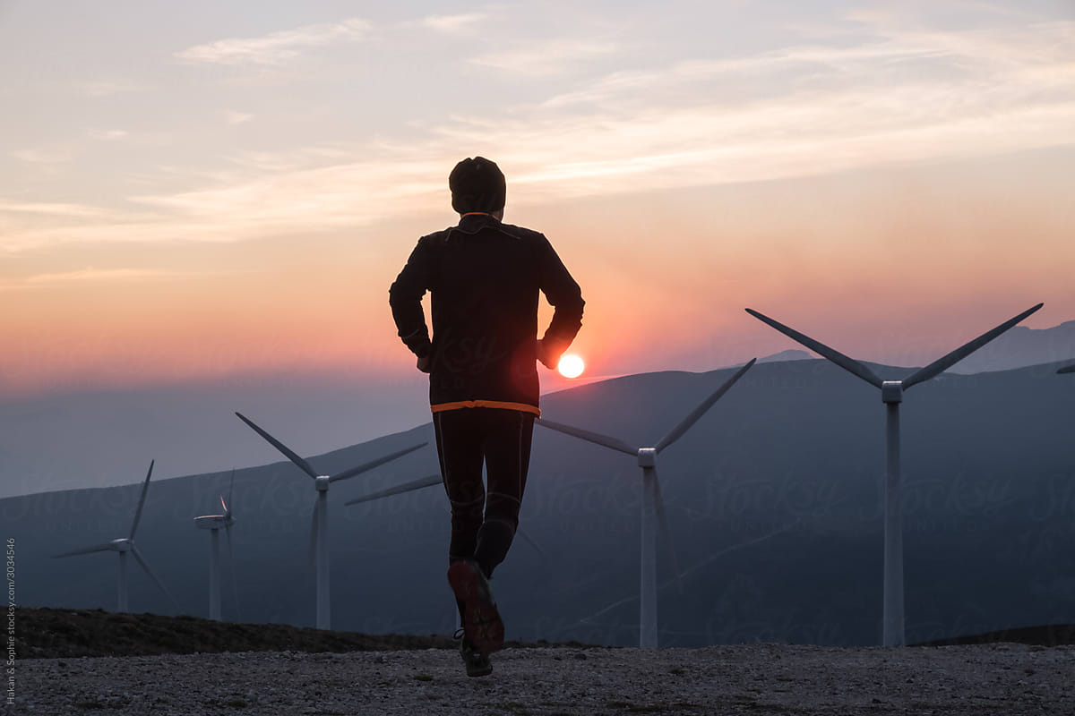 man running towards wind generators in the setting sun