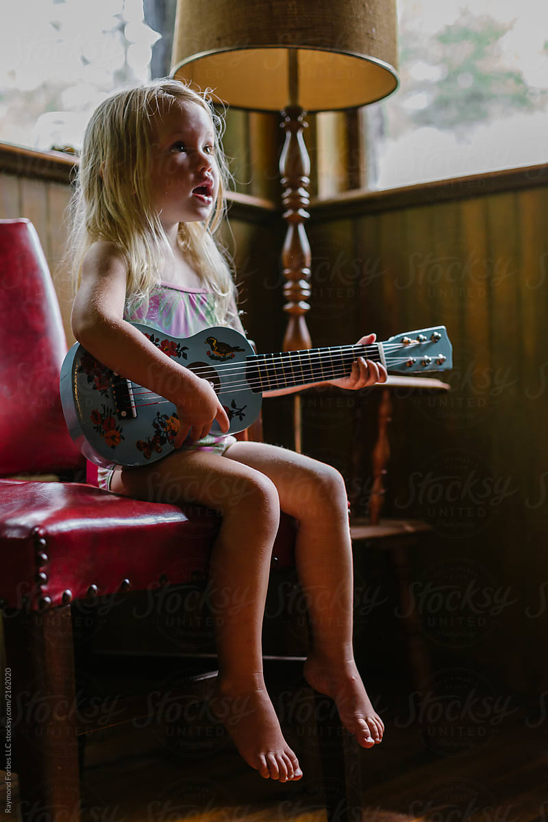 Young Singer Seated on Red Chair with ukulele
