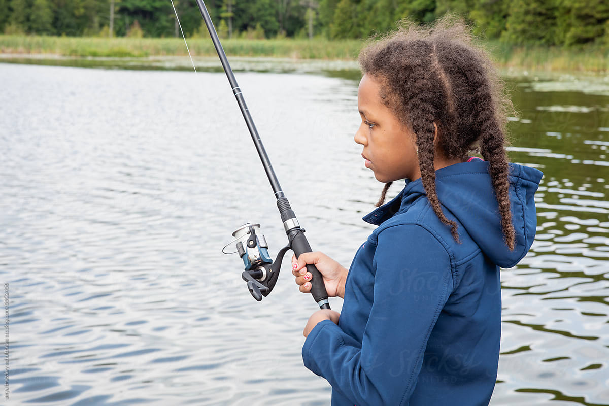 Young girl holding a fishing rod and fishing in a lake