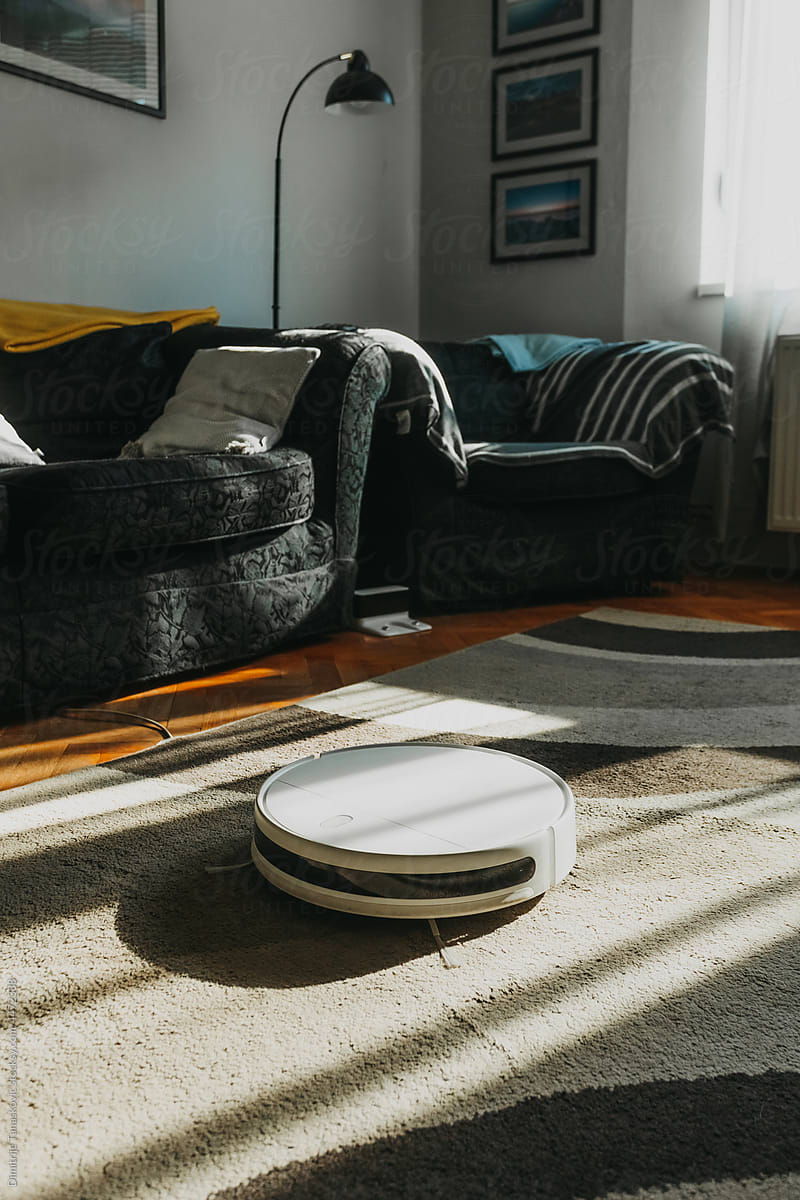 White Robot Vacuum Cleaner In Sunny Room.