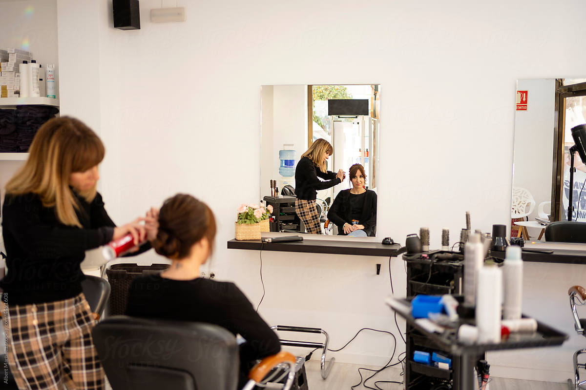 Hairdresser finishing hairdo of client in studio