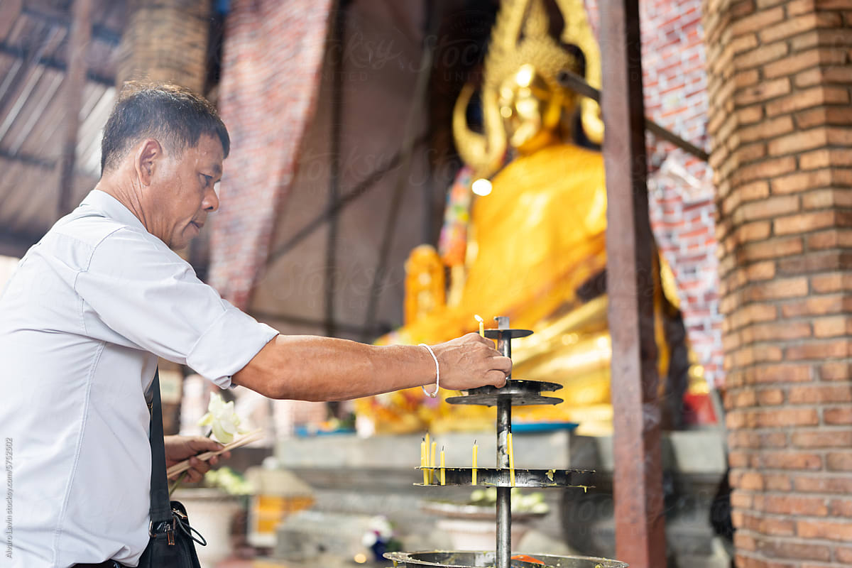 Thai man with candle in Buddhist temple.