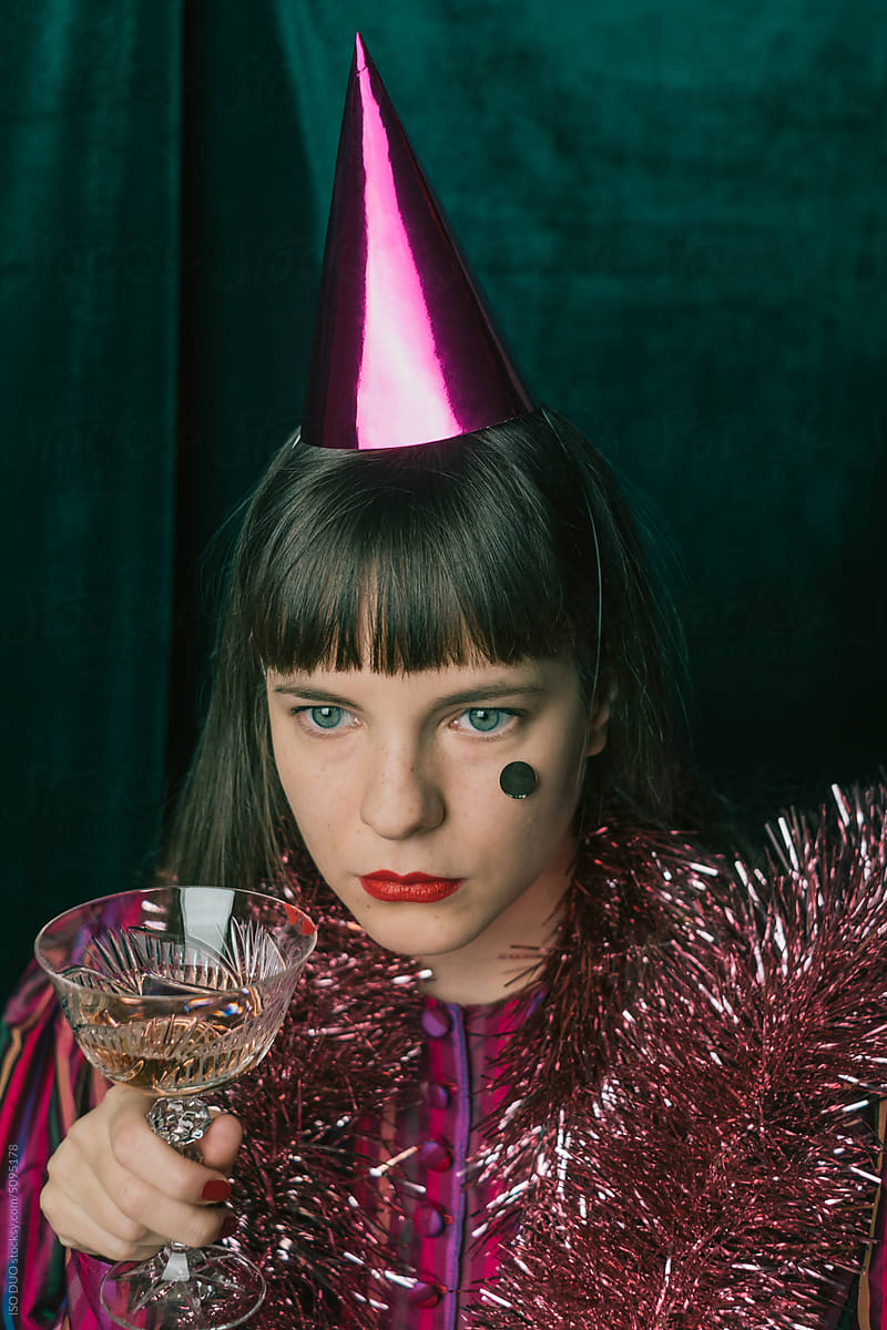 A woman in a pink blouse with a party hat drinking Rose wine