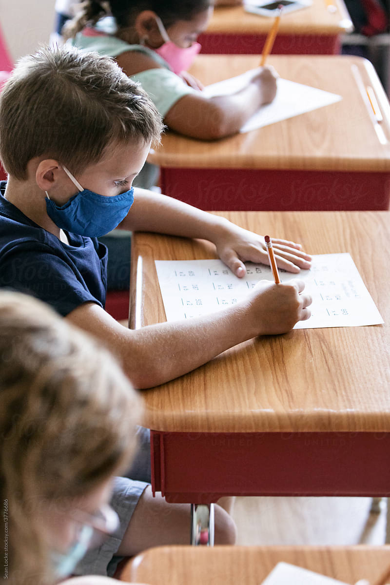 School: Student With Face Mask Works On Math Sheet