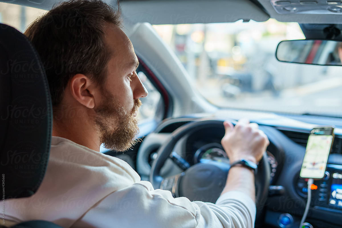Young man driving car using mobile navigation app