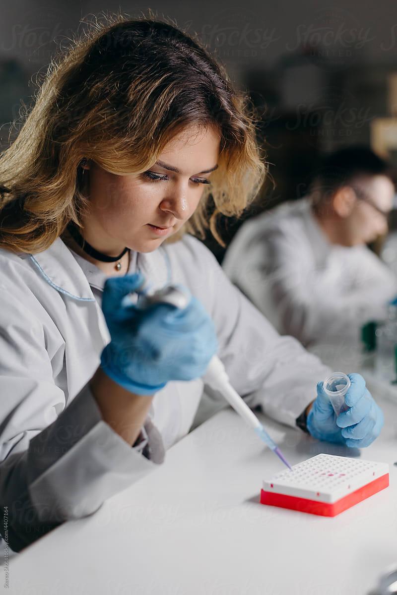 Attentive woman adding reagent to samples in lab