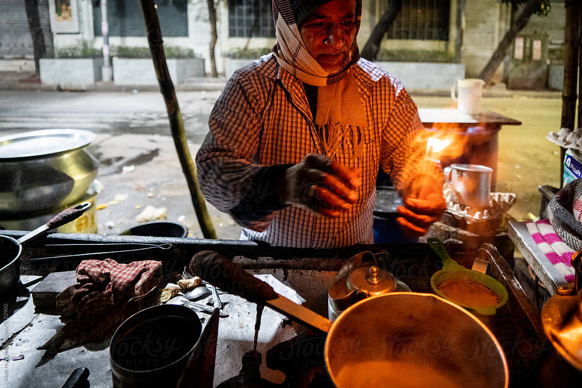 A street food vendor lights nag champa incense on the street in India