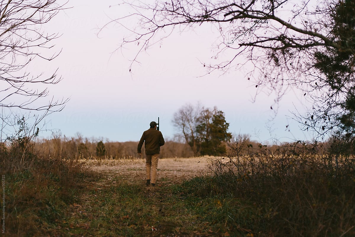 Person Walking Out Of Woods Into Field With Gun While Hunting In Wild by Stocksy  Contributor Matthew Spaulding - Stocksy