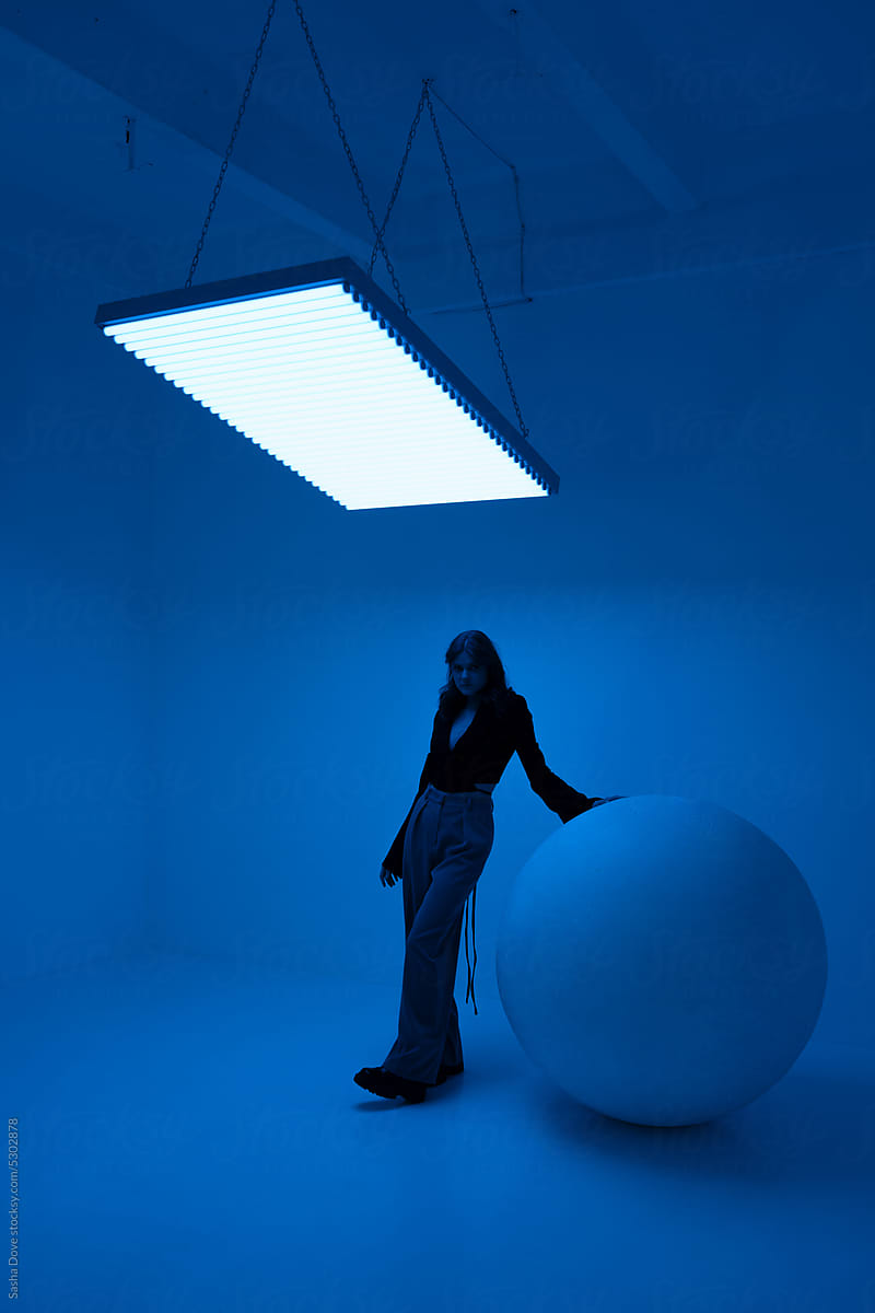 Young female standing in a room filled with blue light