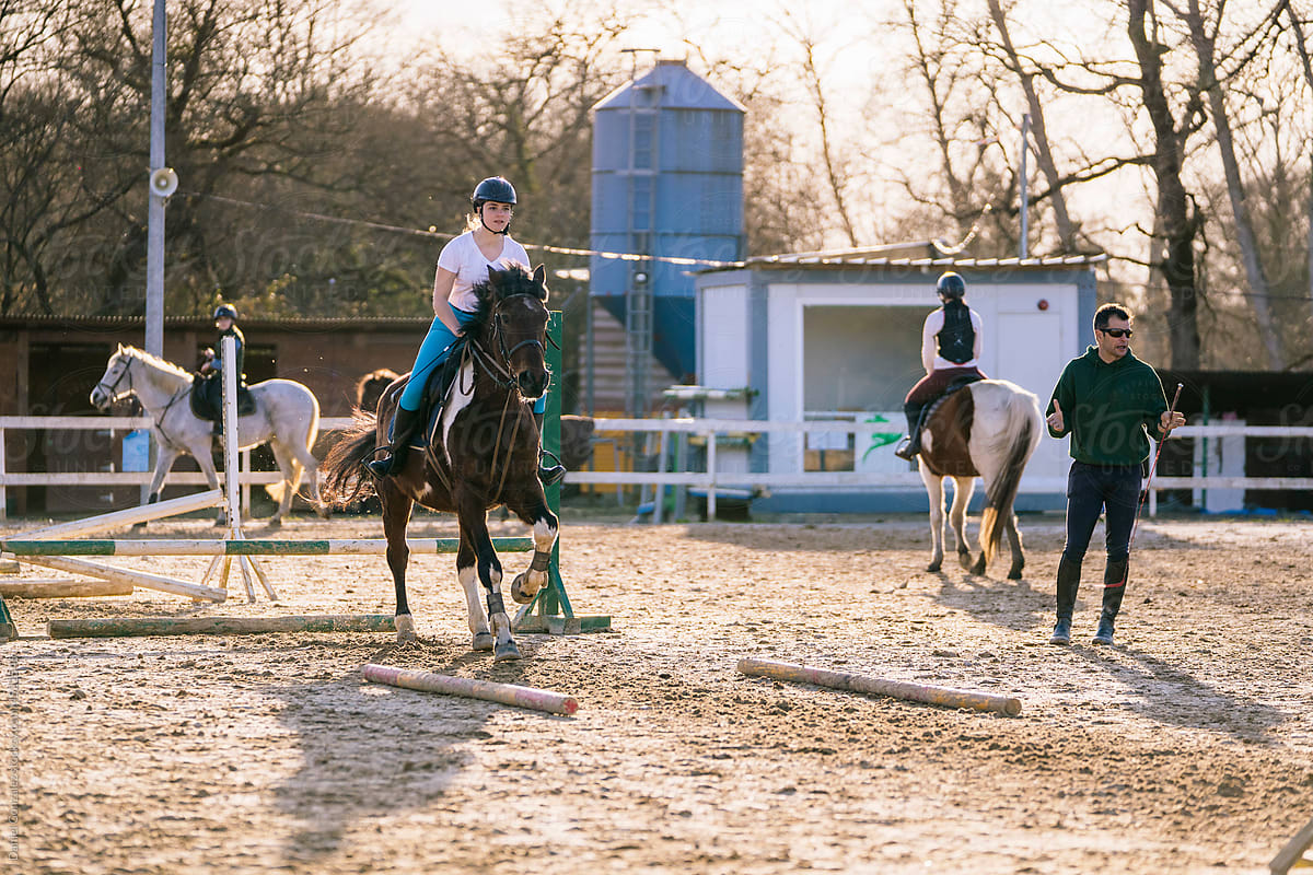 Male trainer instructing ladies practicing horse riding
