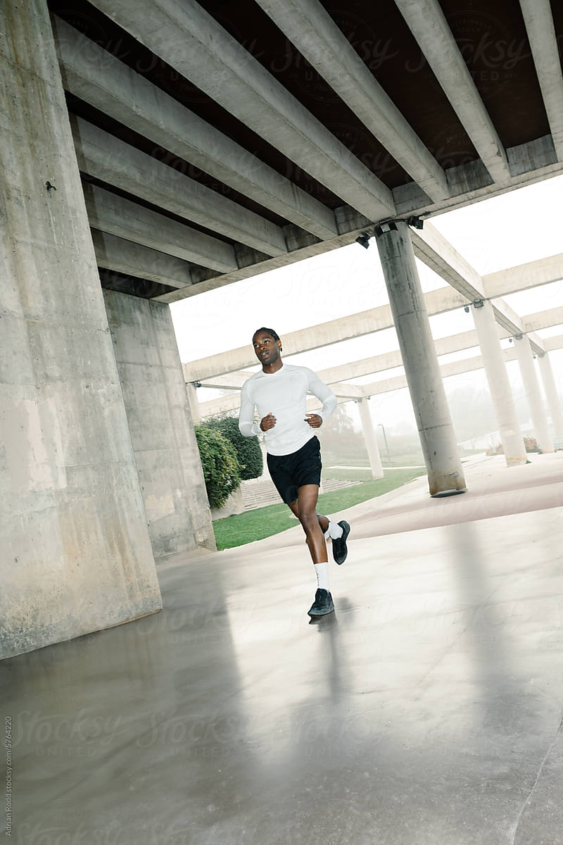 A Black man builds endurance by running in an empty street