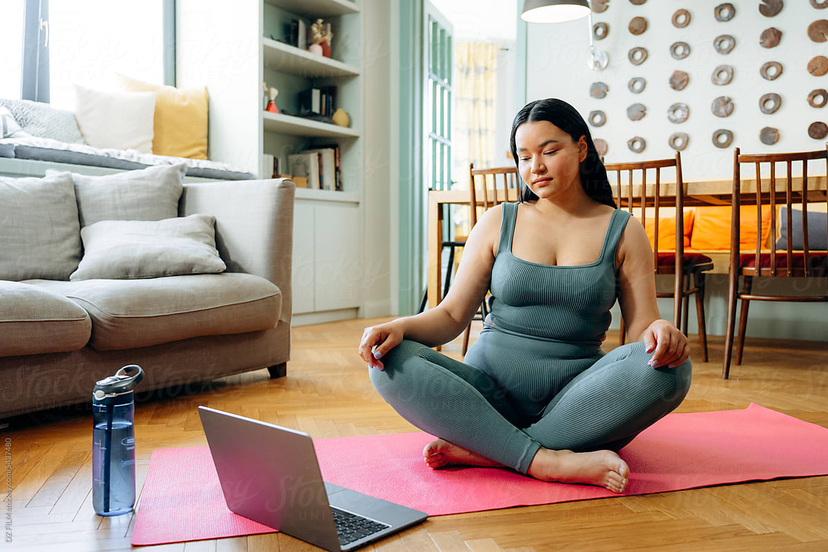 A woman is sitting in the lotus position at home