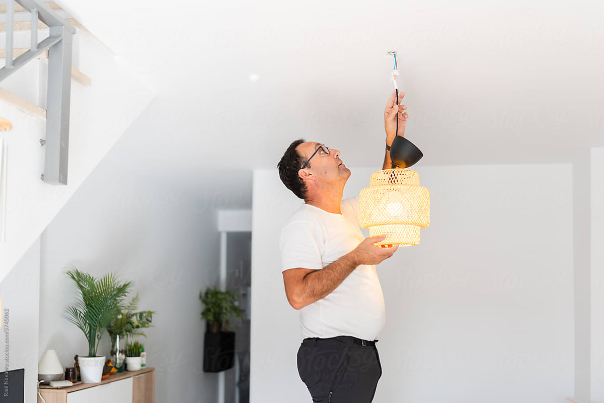 senior man placing a ceiling lamp at home.