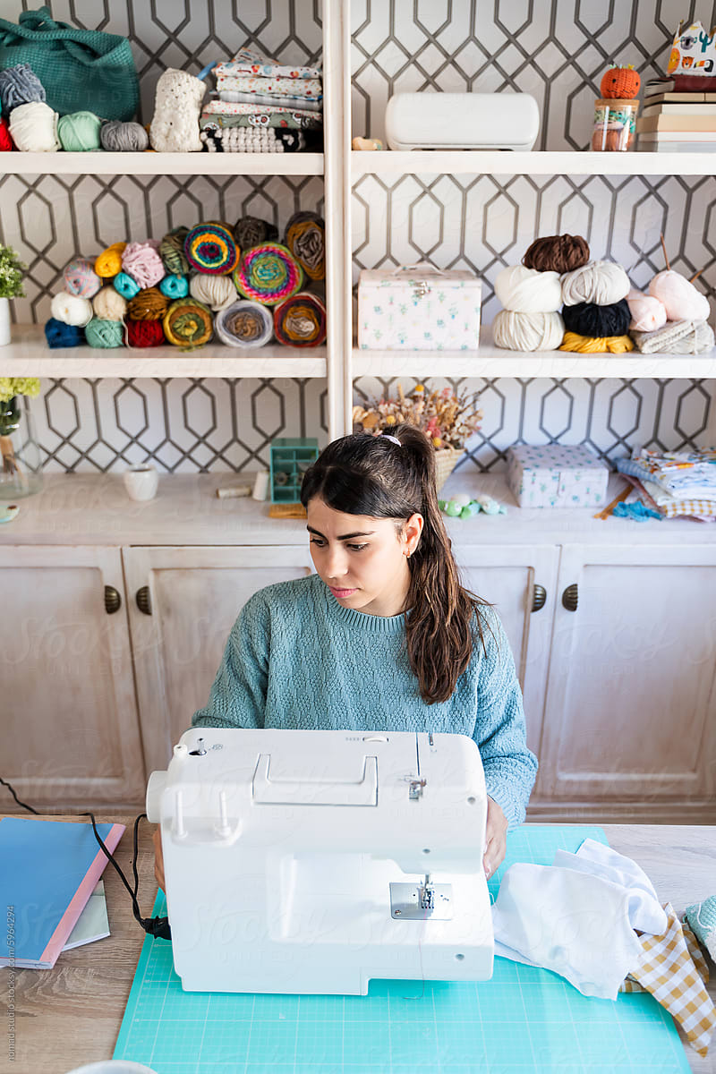 Craftswoman sewing on a machine at home workshop