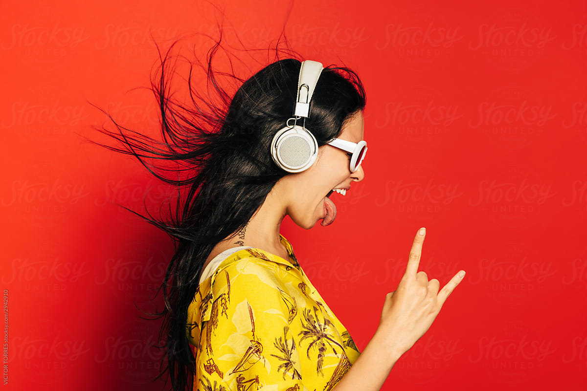 "Excited Young Woman Listening To Music With Headphone Over Red
