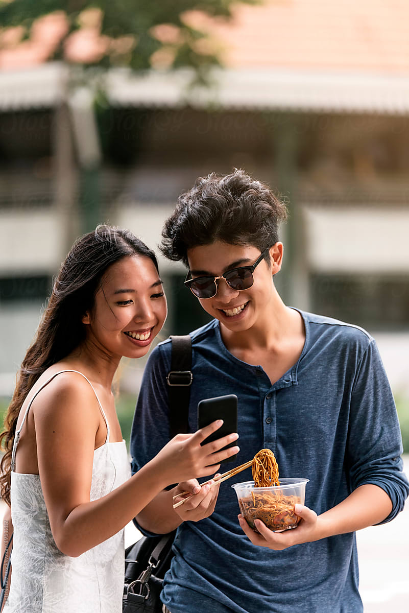 Young asian couple using mobile in the street.