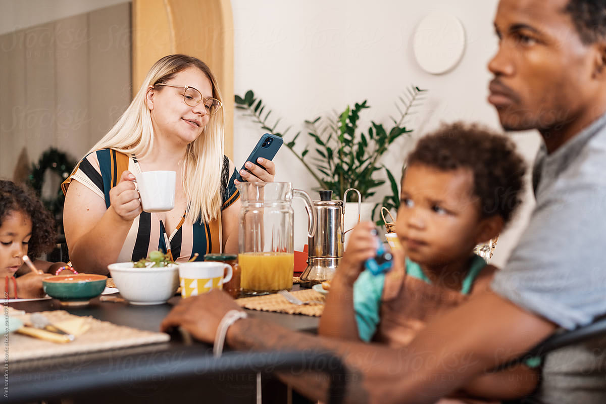 Woman Looking At The Phone During Family Breakfast