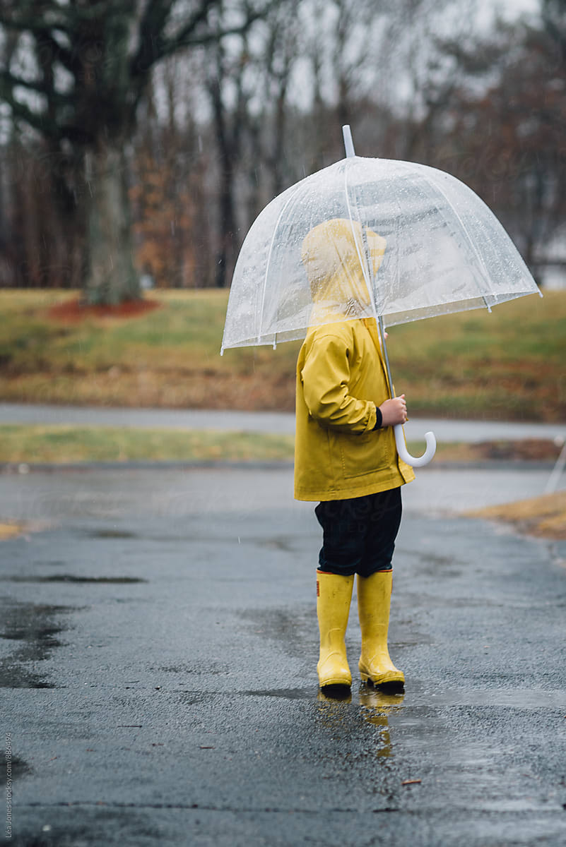 little boy standing under an umbrella in the rain