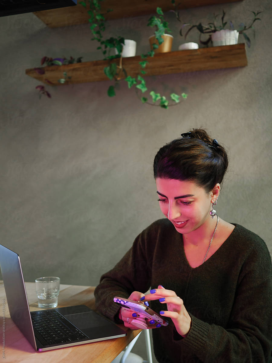 Young woman works on laptop and smartphone in cafe