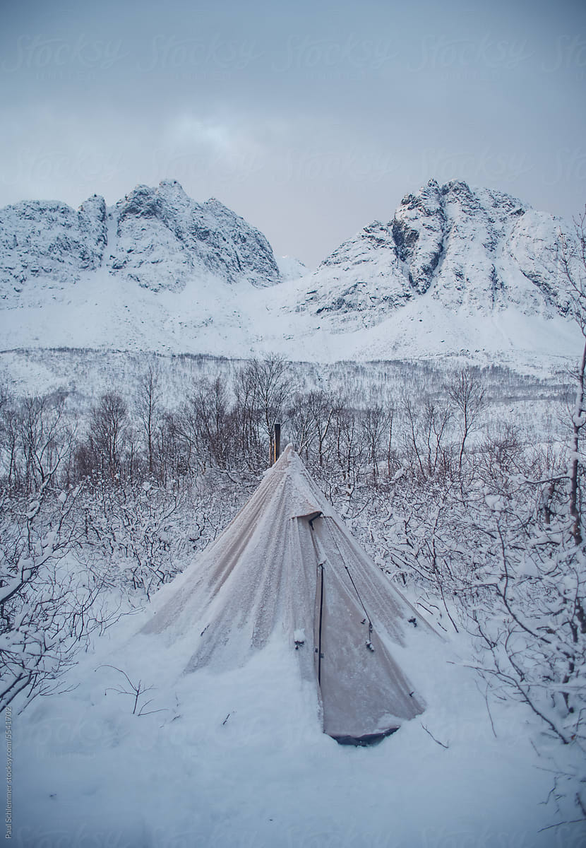 Winter camping in a canvas tent ,snow covered mountains background
