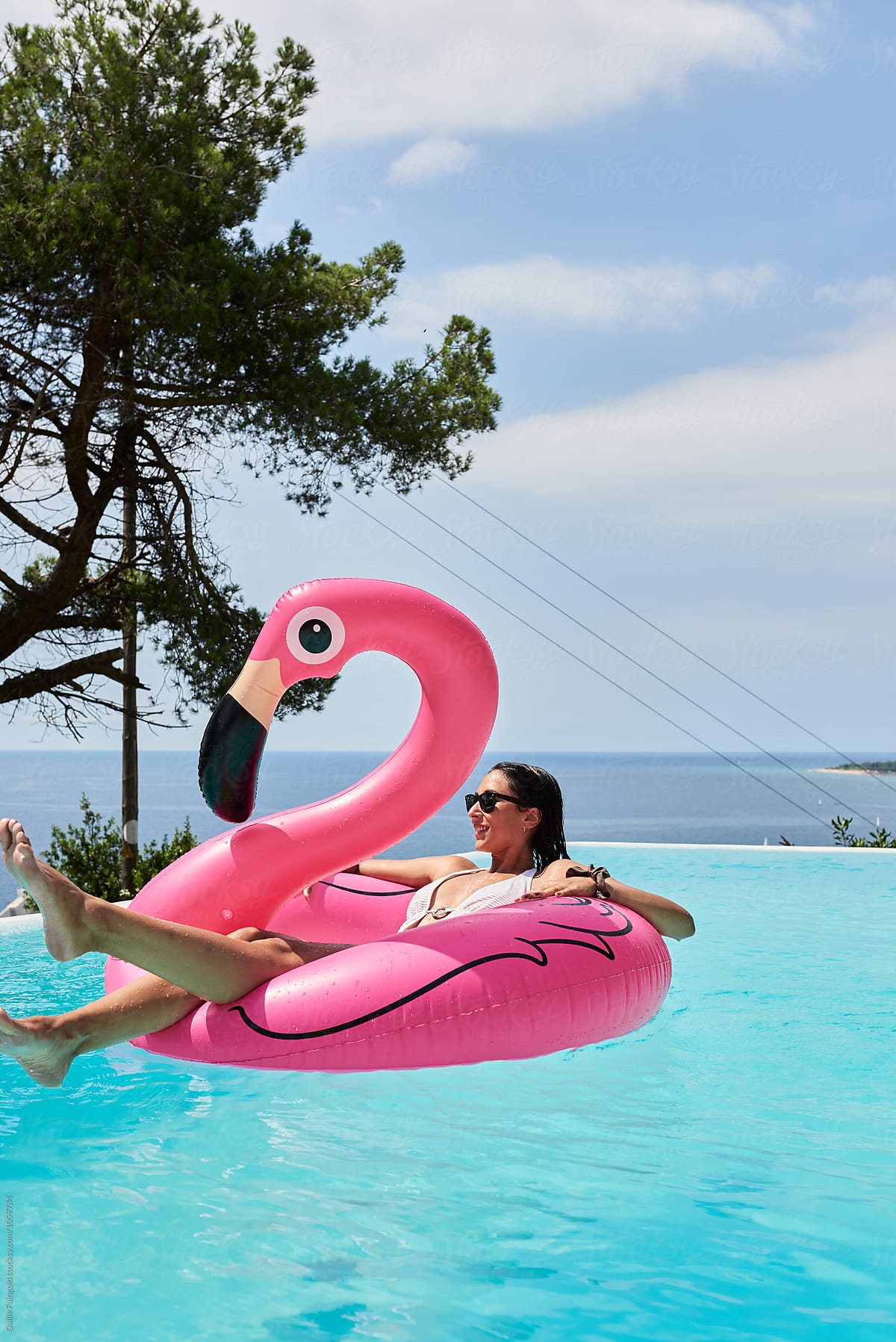 Smiling brunette floating on flamingo air mattress