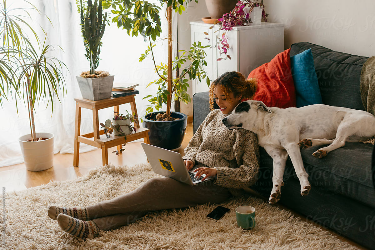 Teenager at home with dog relaxing while using laptop
