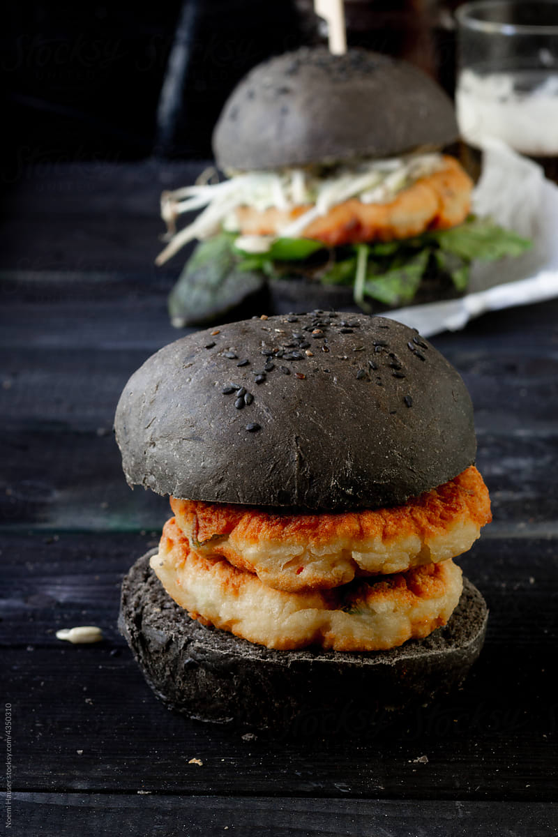 Double patty fish burger in black bun with sesame