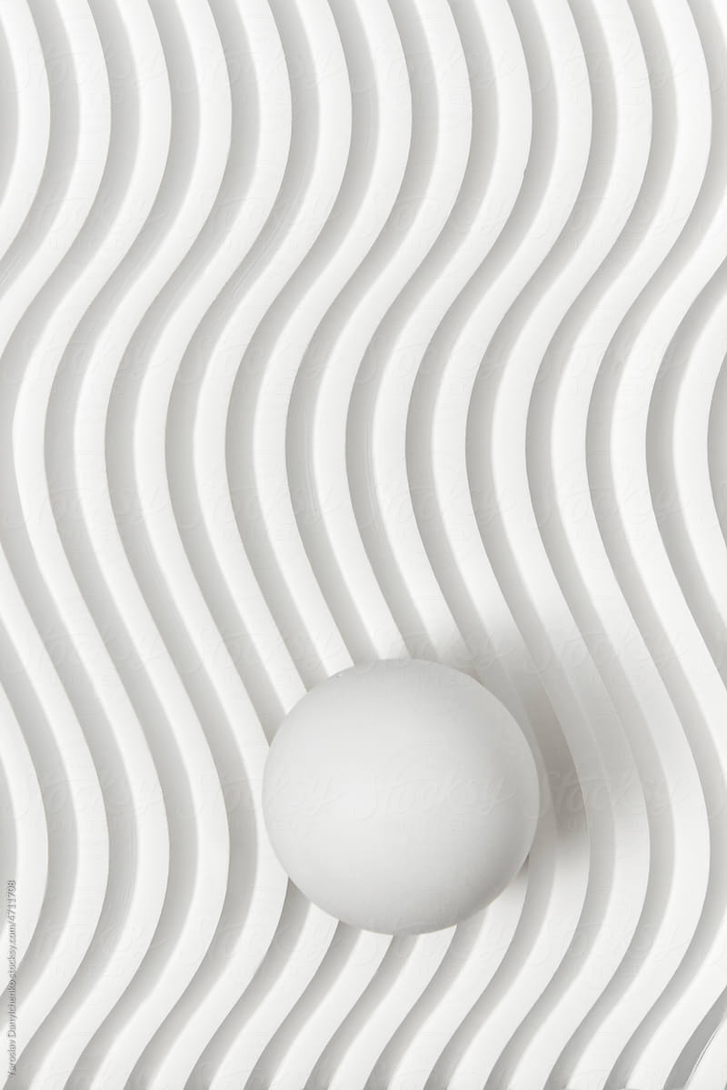 White ribbed background with sphere on top.
