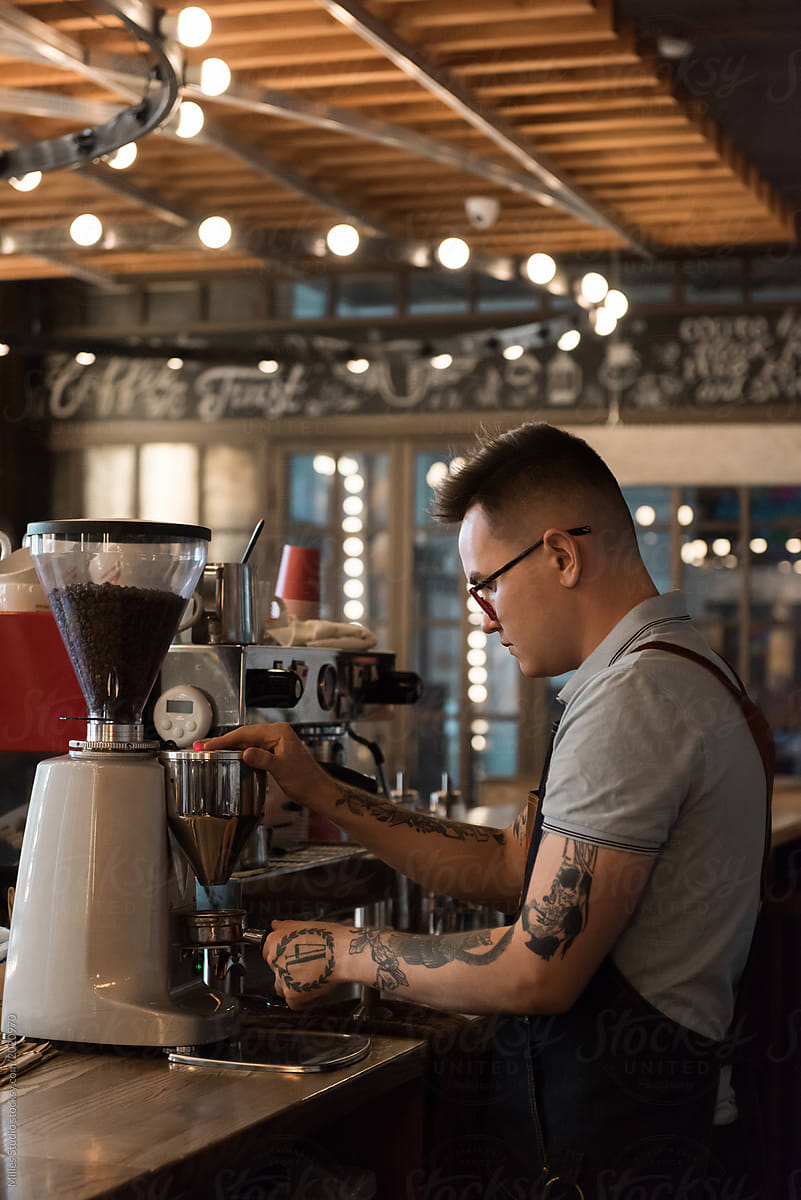 Tattooed barista grinding fresh coffee