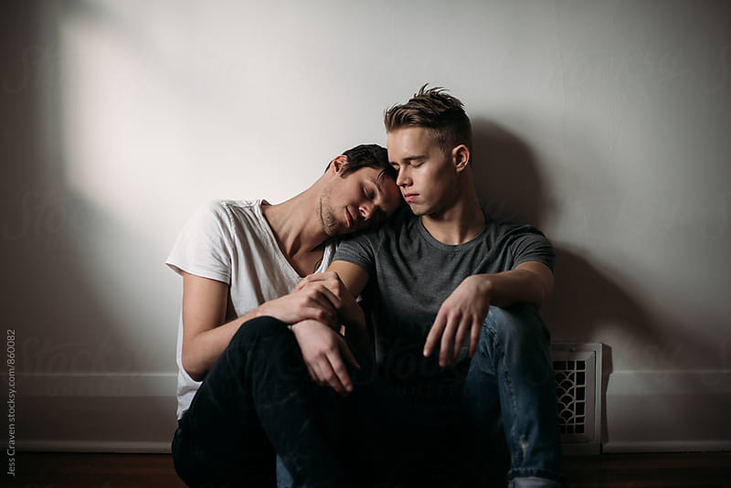 Young gay male couple in love sitting on bedroom floor