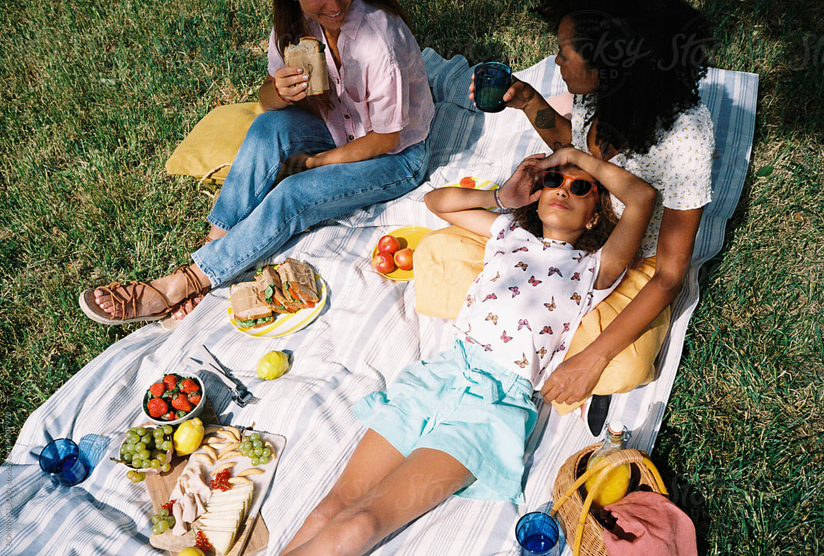 Multiethnic lesbian couple with their daughter enjoying picnic