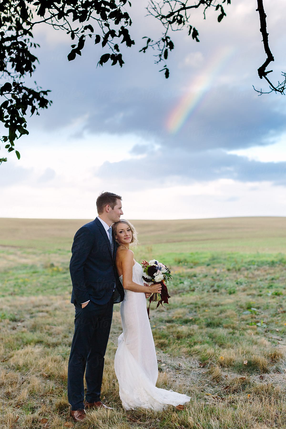 Beautiful Wedding Couple in Field under Sky with Rainbow