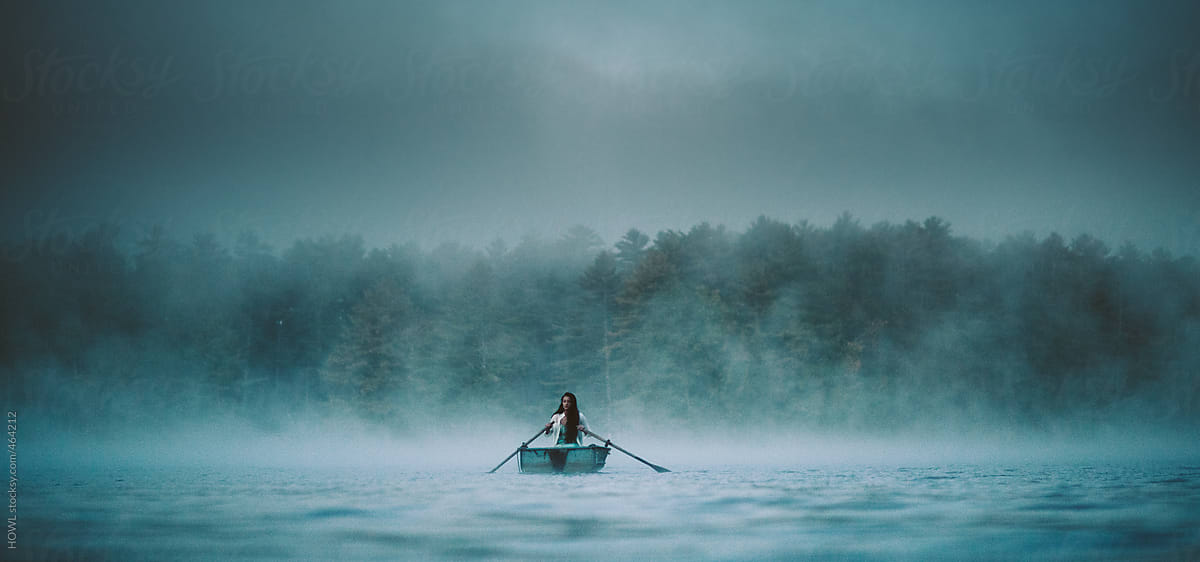 Mystical woman in row boat on a foggy New England morning