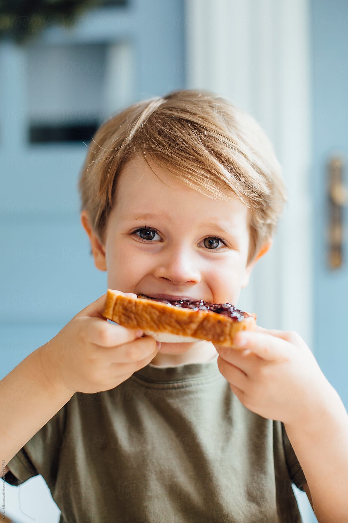 Young boy eating toast with jam for breakfast
