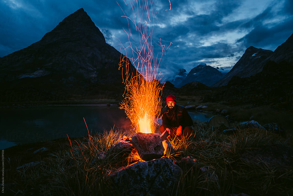 Tourist sitting at burning bonfire on shore