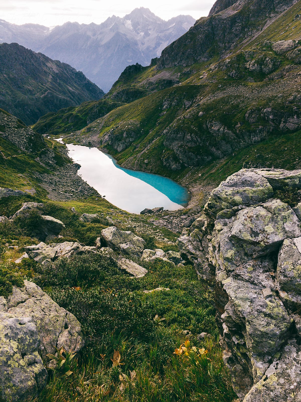 "Turquoise Alpine Lake Surrounded By Green Grass And Peaks" by Stocksy