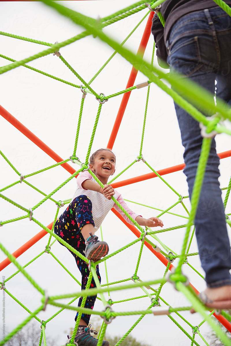 Young Child Happily Exploring A Playground Rope Climber by