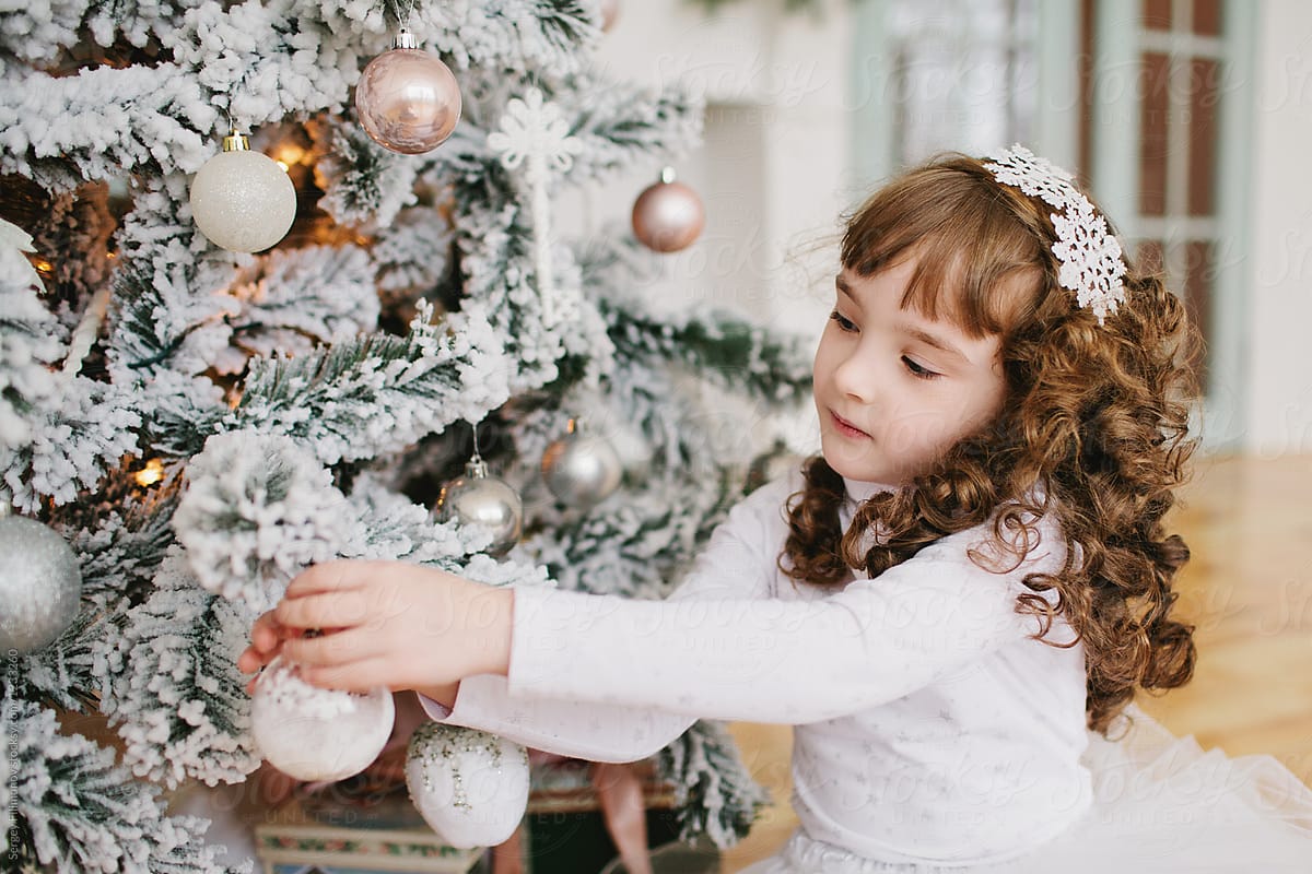 Girl decorating white Christmas tree