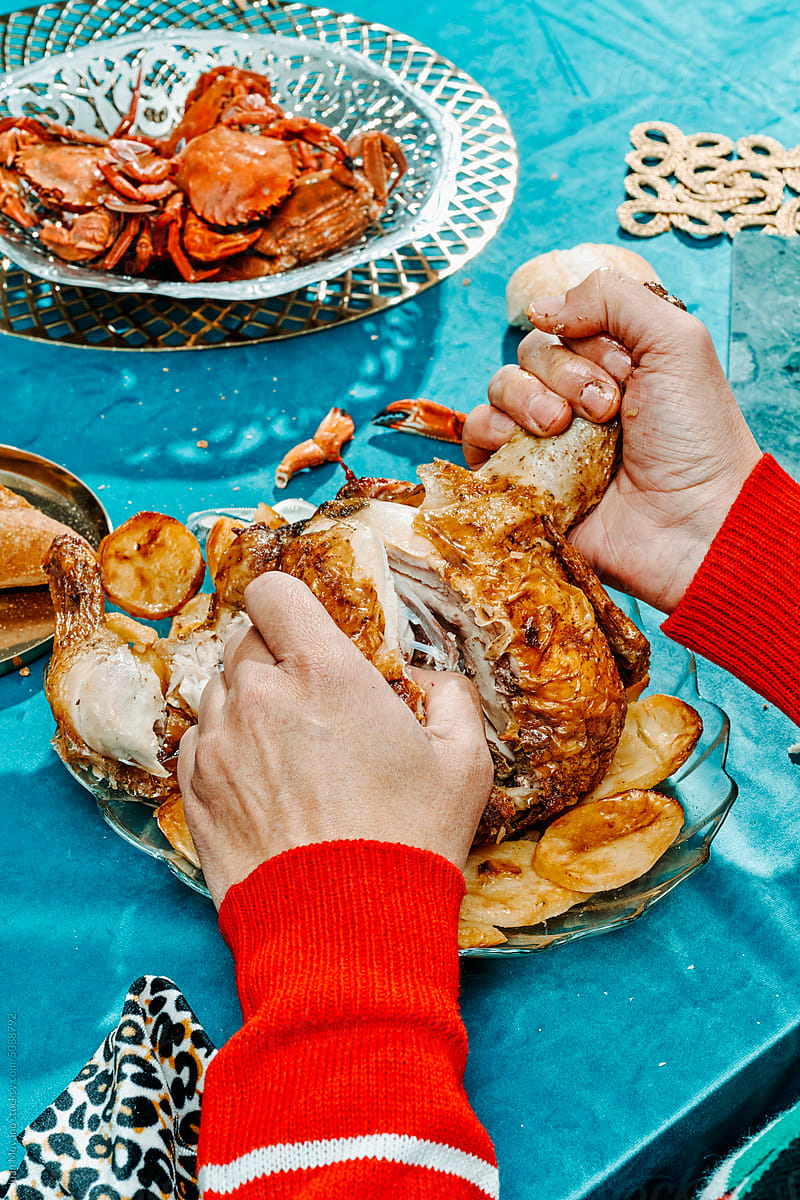 man rips a roast turkey with his hands