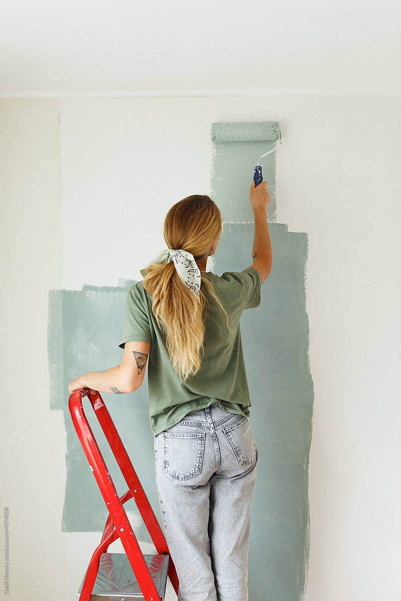 Anonymous female on ladder painting wall