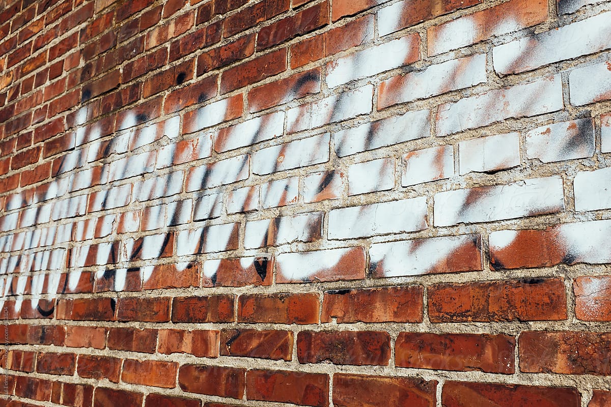 Spray paint covering graffiti on old brick wall