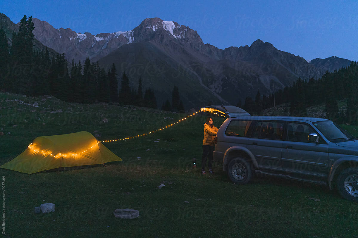 Woman near the car and tent in mountains
