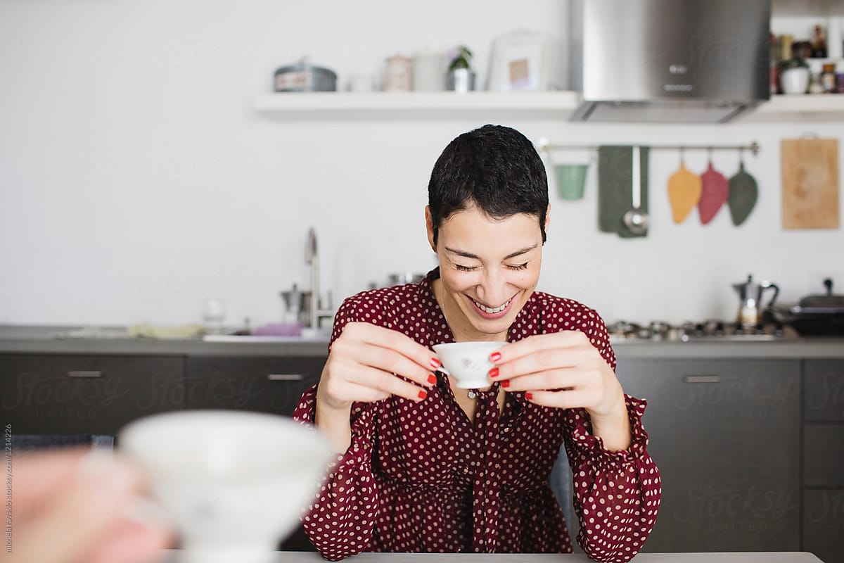 Smiling woman drinking a cup of coffee with friend