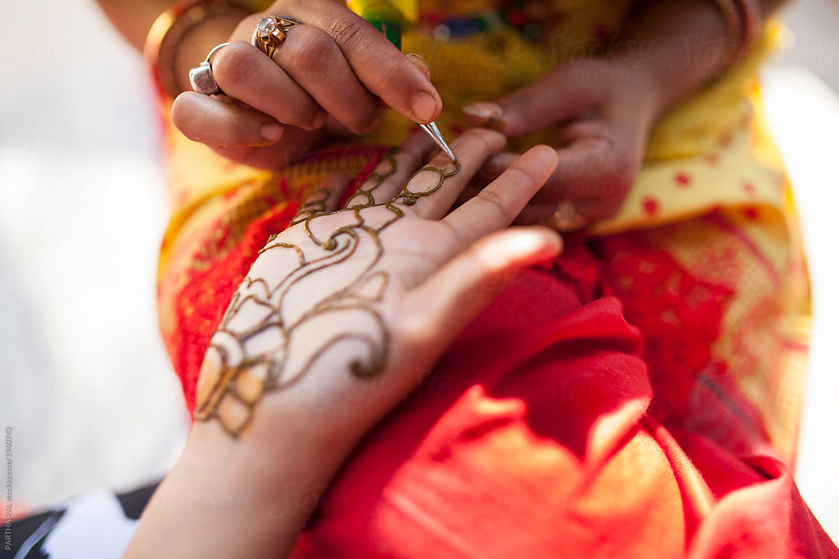 woman applying mehendi in hand in a hindu marriage occassion
