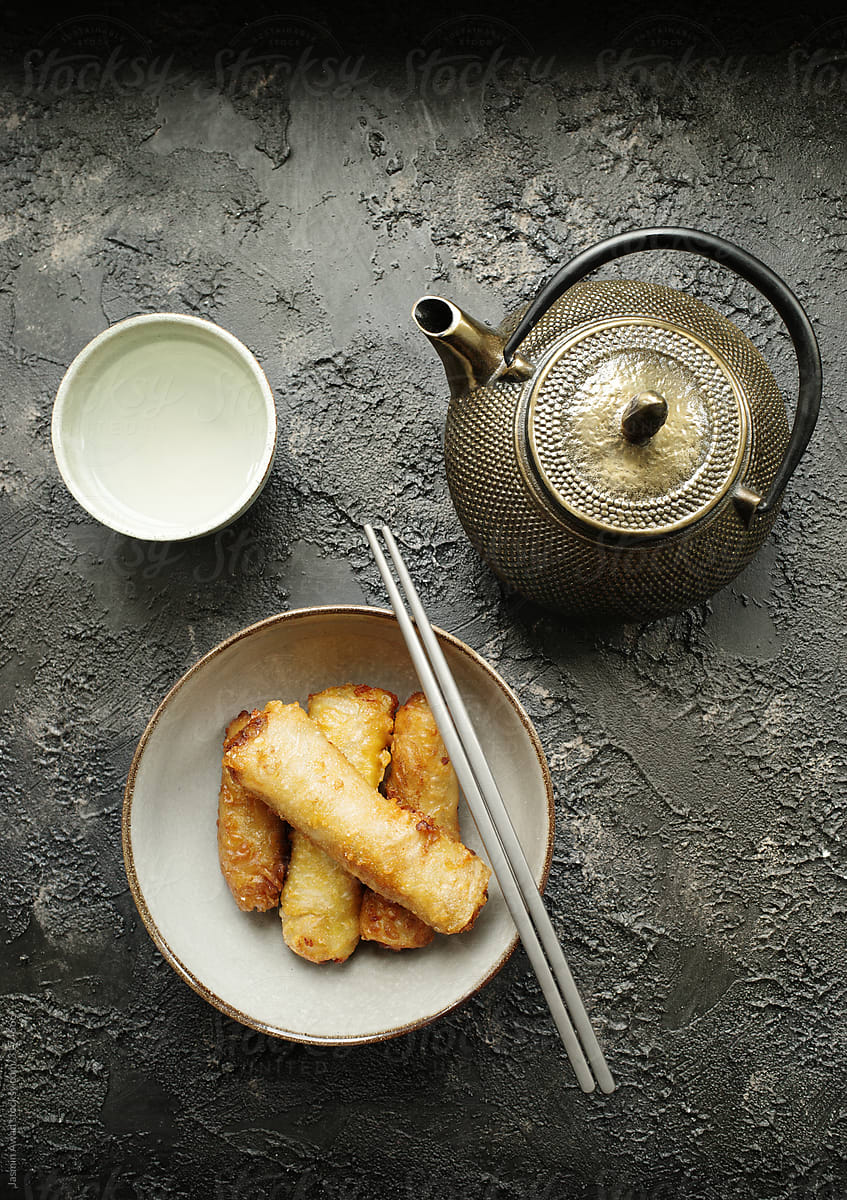 Fried spring rolls with green tea and old fashioned metal teapot