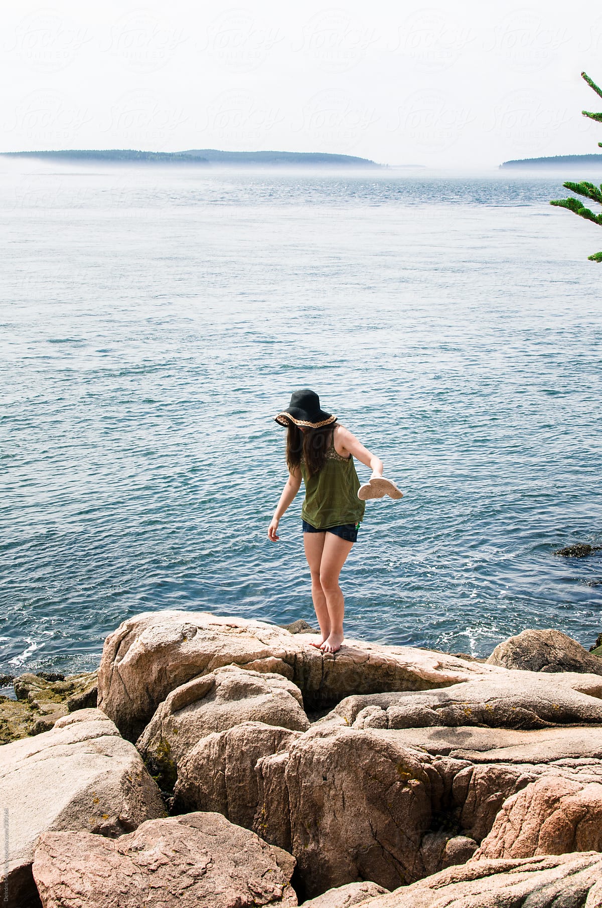 girl walking on rocks by ocean