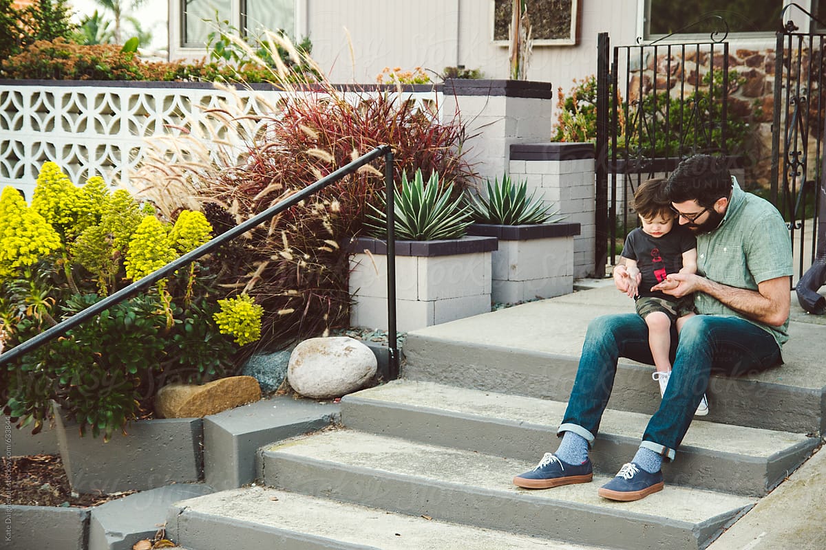 Father and son sitting on front steps of their home.
